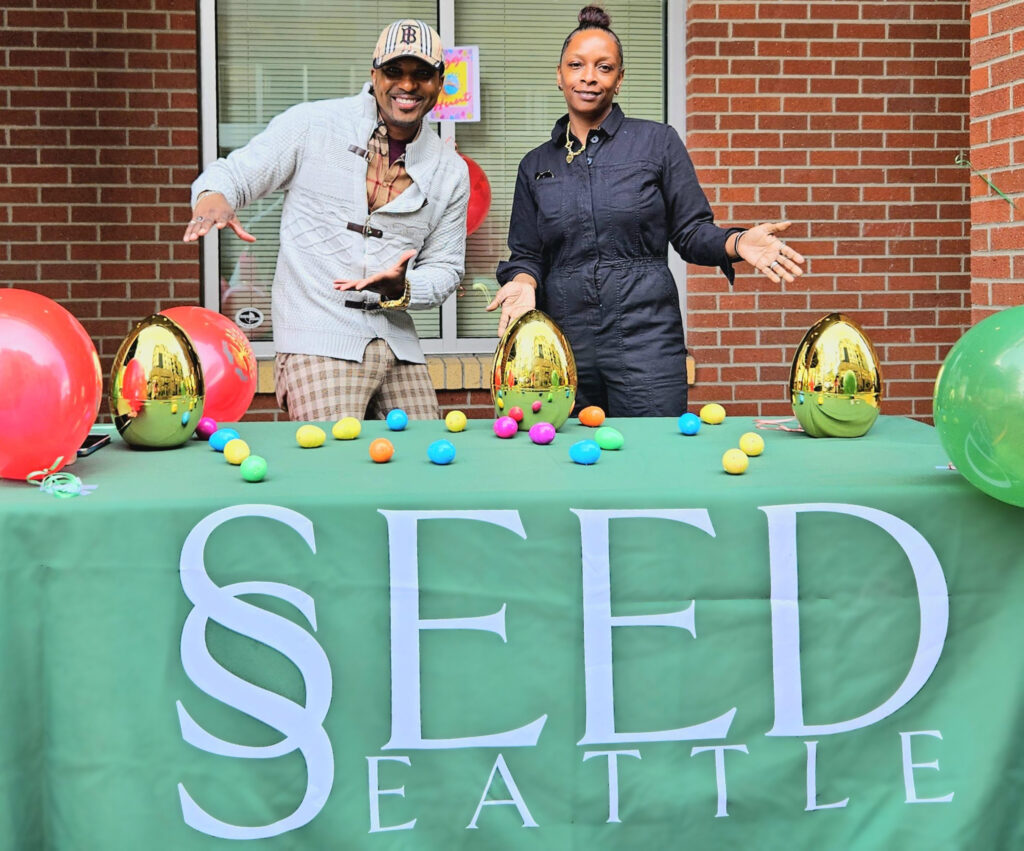 Two people are smiling and displaying Easter eggs